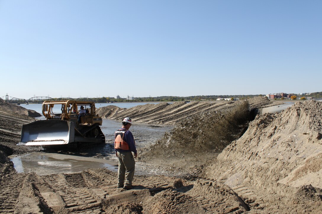 Karl Schmitz, dredging coordinator, Operations Division, checks the discharge pipe at the Dredged Material Management Placement site below Locks and Dam 15 in Rock Island, Ill. After dredging, the material is made available for beneficial use to the City of Rock Island.