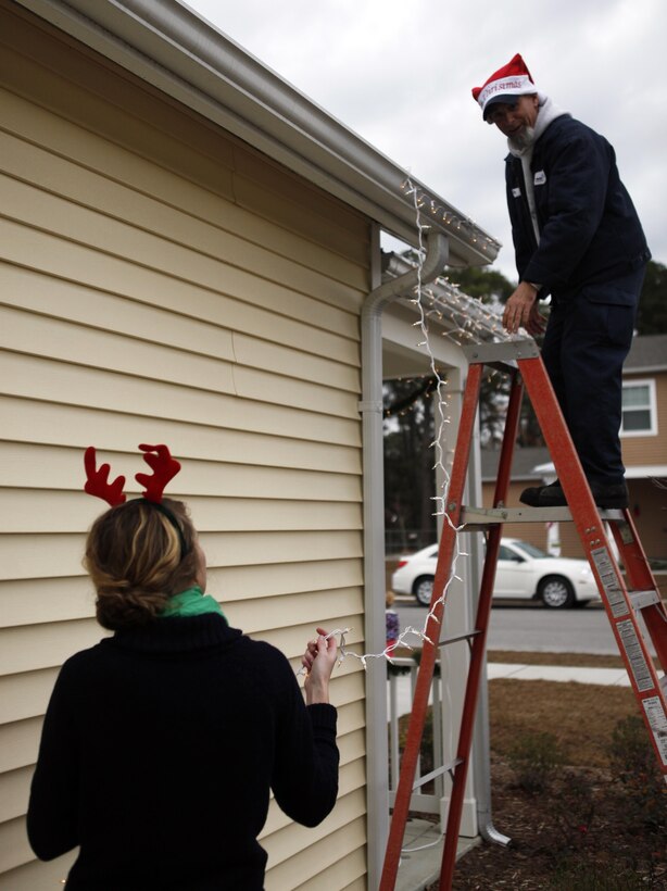 Volunteers from Atlantic Marine Corps Communities housing work to put up lights on homes in Berkley Manor for Elf Day aboard Marine Corps Base Camp Lejeune Dec. 7.  Elf Day was established to assist families of deployed service members or those who may just need a little extra assistance from Santa’s helpers during the busy time.