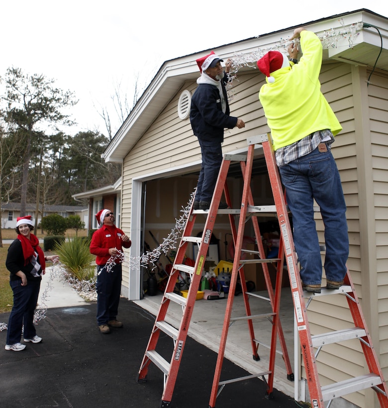 Volunteers from Atlantic Marine Corps Communities housing work to put up lights on homes in Berkley Manor for Elf Day aboard Marine Corps Base Camp Lejeune Dec. 7.  Elf Day was established to assist families of deployed service members or those who may just need a little extra assistance from Santa’s helpers during the busy time.