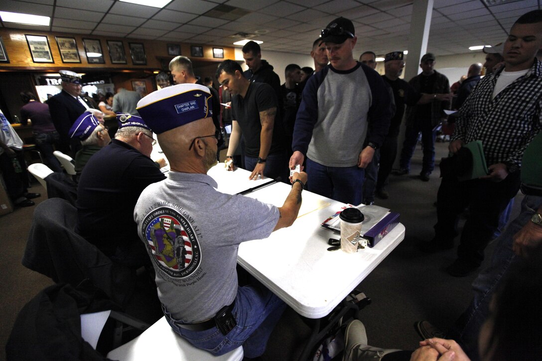 Service members present their military identification cards to show the legitimacy of their Purple Heart award at a check-writing event hosted by the Military Order of the Purple Heart in Jacksonville, N.C., Dec. 13. MOPH raised approximately $369,000 for service members who were awarded the Purple Heart to be able to travel home this holiday season.