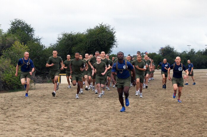 Drill instructors and recruits of Company K, 3rd Recruit Training Battalion, lead their recruits in a sprint during recruit training aboard Marine Corps Recruit Depot San Diego Dec. 18. The company ran quarter-mile sprints in intervals around a trail for physical training. For recruits, this was their first day of training aboard which initially set the pace for the next three months.