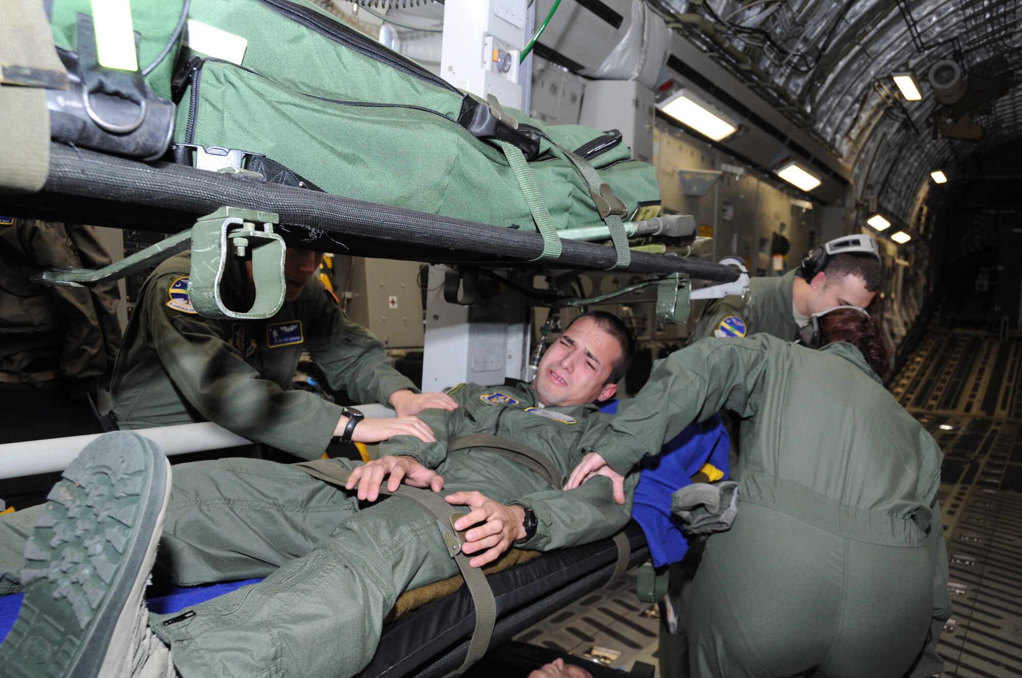 Senior Airman Storm Ford, 315 Aeromedical Evacuation Squadron medical technician, exhibits signs of extreme discomfort in his left leg causing other 315 AES members to respond quickly and provide comfort, care and treatment of signs and symptoms during a training flight Jan. 1, 2012 over Joint Base Pearl Harbor-Hickam, Hawaii. The AES mission allowed the medical team to practice their skills on various elements of patient care and they were given multiple training scenarios to combat in flight emergencies. (U.S. Air Force Photo/Staff Sgt. Shane Ellis)