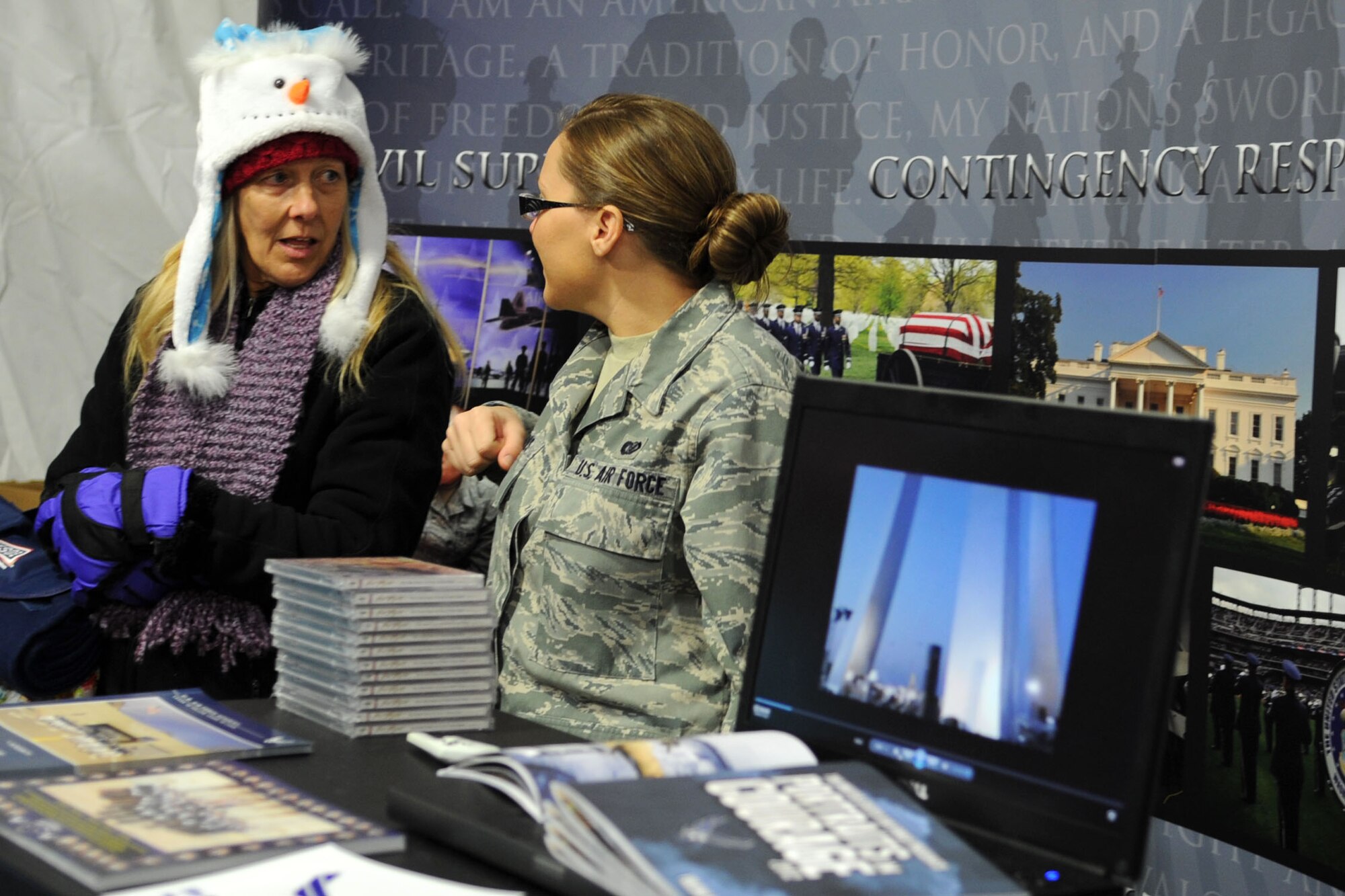 Senior Airman Tabitha N. Haynes, Air Force District of Washington public affairs community outreach specialist, explains her job to a football fan at the Military Village Expo before the 2012 Military Bowl at RFK Stadium Dec. 27, in Washington, D.C. Each military service set up displays and information booths at the expo for spectators of bowl game between San Jose State University and Bowling Green. (U.S. Air Force photo by Tech. Sgt. Tammie Moore)