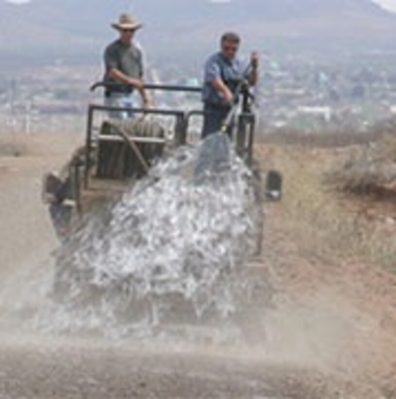 Dust mitigation on a U.S. Border Patrol road, using trailer-mounted hydroseeder pulled by a HMMW.