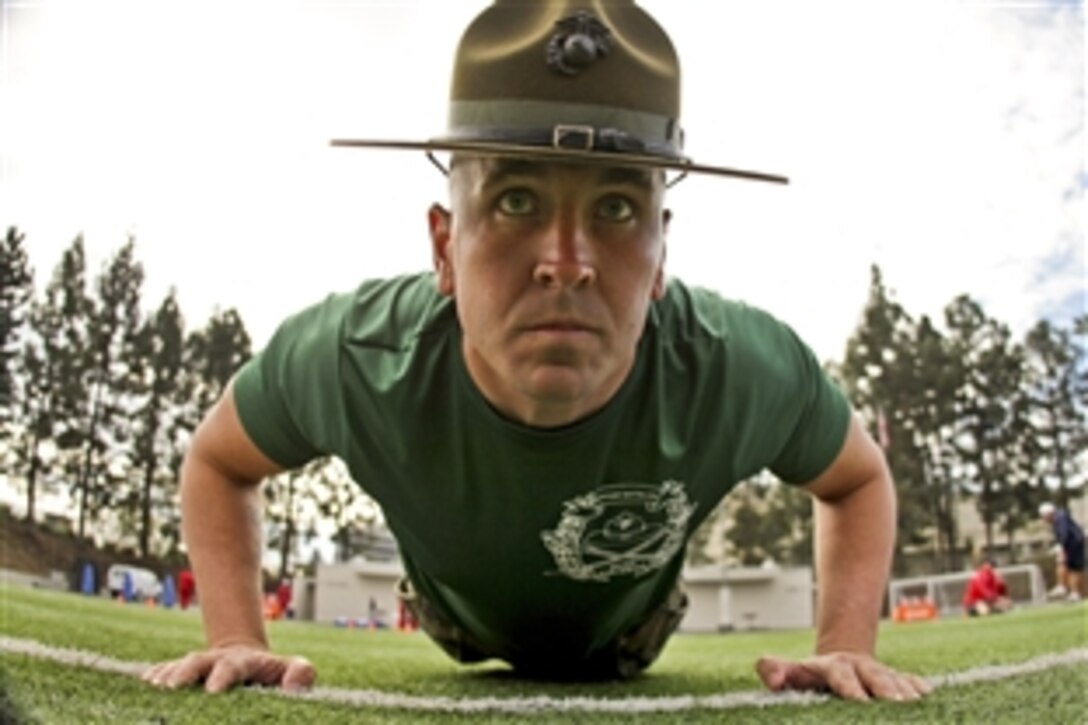 Marine Corp Sgt. Mathew Lee perfoms push-ups after watching members of the Semper Fidelis All-American West team exercise at Santa Ana Stadium in Santa Ana, Calif., Jan. 1, 2013. More than 100 football players from across the country will participate in the Semper Fidelis All-American Bowl on Jan. 4, 2013. Lee is a drill instructor.