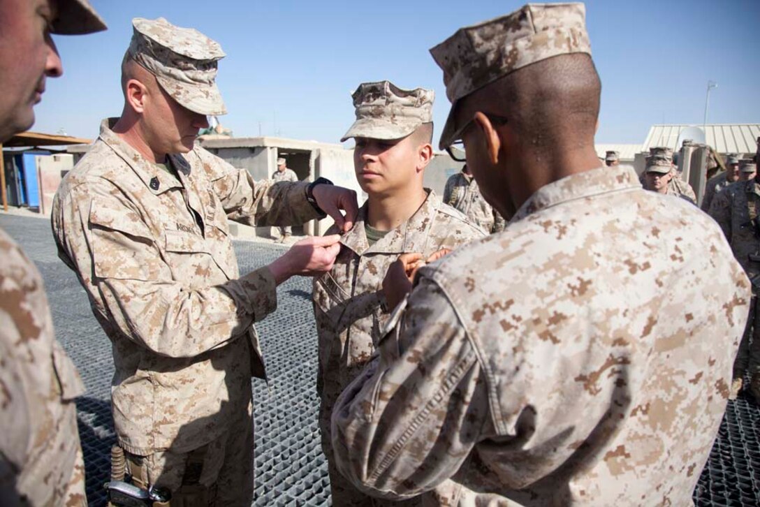 U.S. Marine Corps Sgt. Robert J. Bell, center, with Headquarters Company, Regimental Combat Team 7 (RCT-7), is promoted to the rank of Staff Sgt. on Camp Leatherneck, Helmand province, Afghanistan, Jan. 1, 2013. Bell is currently deployed to Afghanistan in support of Operation Enduring Freedom. (U.S. Marine Corps photo by Staff Sgt. Ezekiel R. Kitandwe/Released)