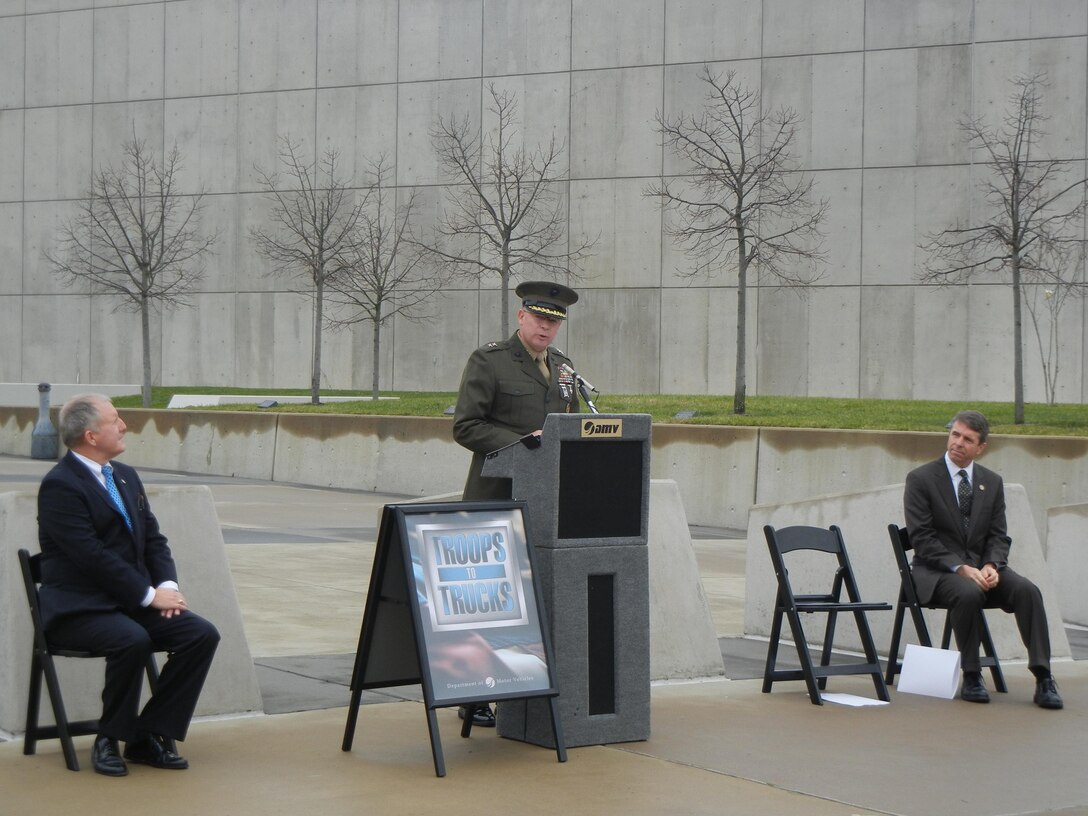 Virginia Department of Motor Vehicles Commissioner Richard Holcomb, left, and U.S. Rep. Rob Wittman (Va.-1) look on as Maj. Gen. James Kessler, commander of Marine Corps Installations Command, addresses the audience at the National Museum of the Marine Corps on Dec. 17. 