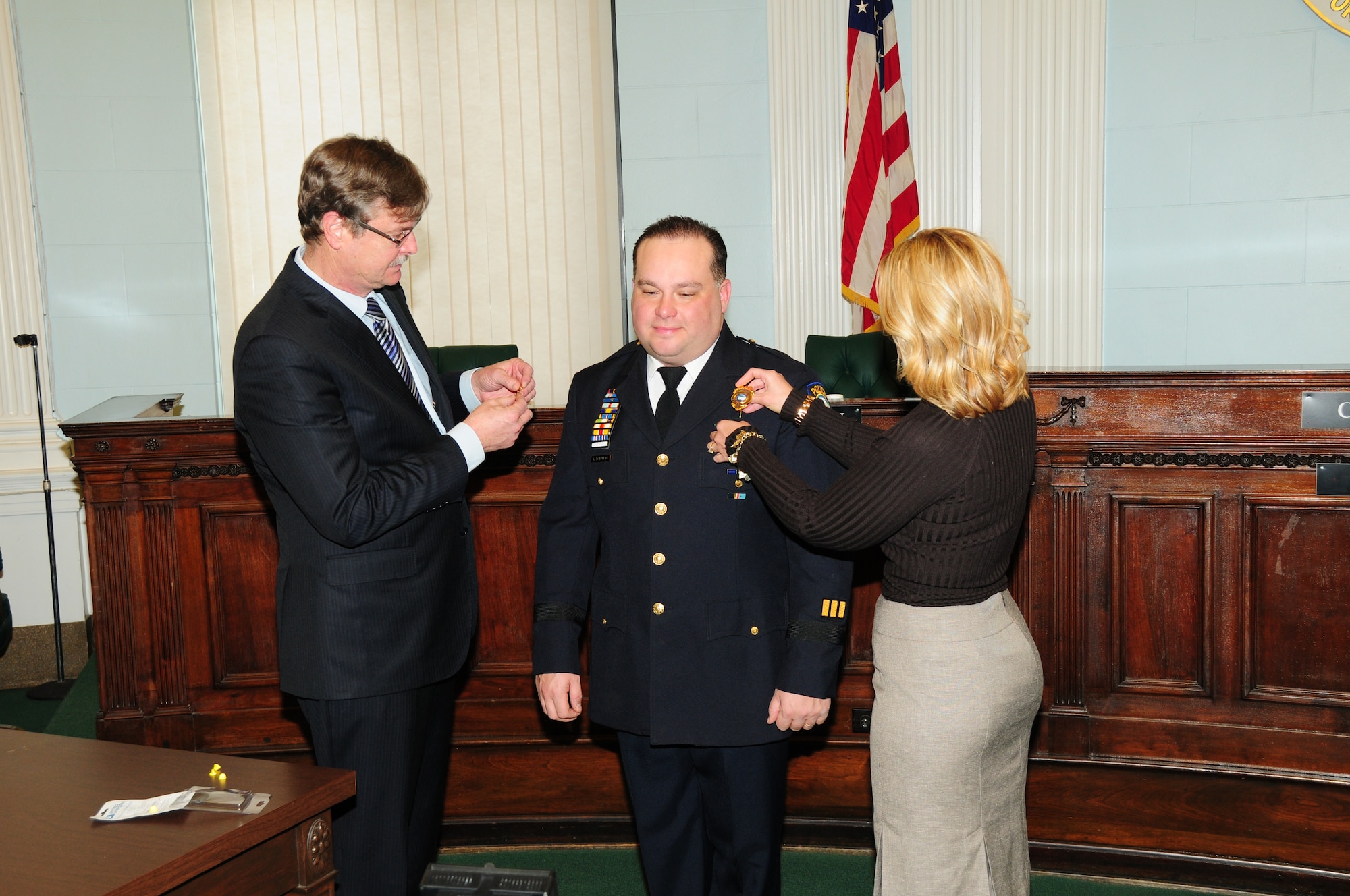 Major Bryan DalPorto, 107th Airlift Wing's Force Support Squadron (FSS) Commander was named the new police superintendent for the city of Niagara Falls N. Y.  Mayor Paul Dyster and wife Eveyln DalPorto pin the badge and rank on Jan, 4, 2013 (Air National Guard  Photo/Senior Master Sgt Ray Lloyd)

