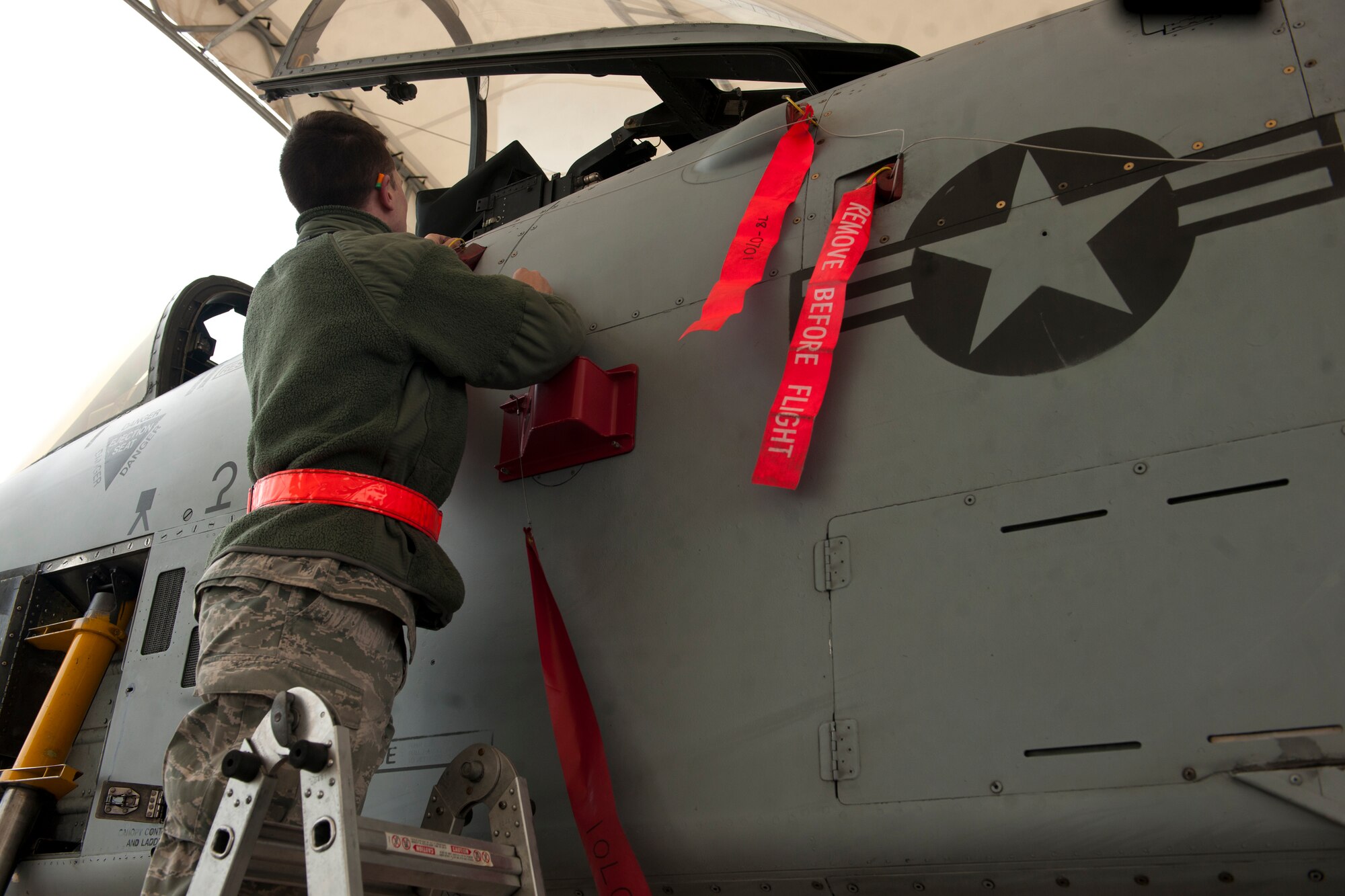 U.S. Air Force Airman 1st Class Nathan Durland, 75th Aircraft Maintenance Unit weapons load crew member, places flags on an A-10C Thunderbolt II at Moody Air Force Base, Ga., Jan. 3, 2013. The flags remind the crew to check the A-10’s ordnance during their final inspection. (U.S. Air Force photo by Airman Alexis Grotz/Released)