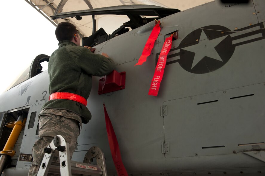 U.S. Air Force Airman 1st Class Nathan Durland, 75th Aircraft Maintenance Unit weapons load crew member, places flags on an A-10C Thunderbolt II at Moody Air Force Base, Ga., Jan. 3, 2013. The flags remind the crew to check the A-10’s ordnance during their final inspection. (U.S. Air Force photo by Airman Alexis Grotz/Released)