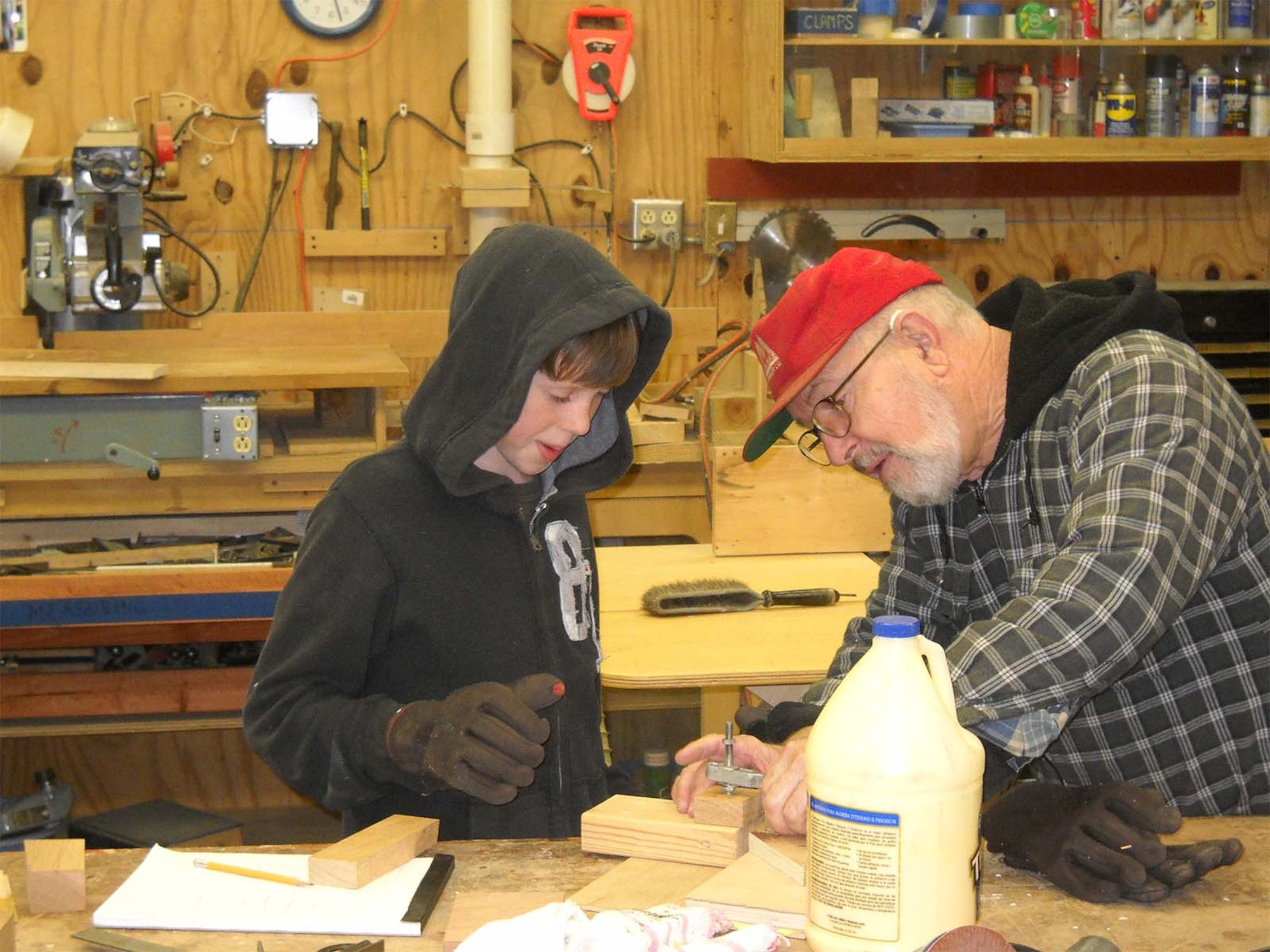 Ed Wares shows his grandson how to build toy cars in Wares' Tennessee workshop.  The woodworker, father of Sabrina Miller, the Scientific & Technical Information Program Manager for the Air Force Technical Applications Center at Patrick AFB, Fla., hand-carved more than 100 wooden toy cars to distribute to orphans at the Chechon Children’s Home, a facility located approximately 75 miles southeast of Seoul.  (Courtesy photo)