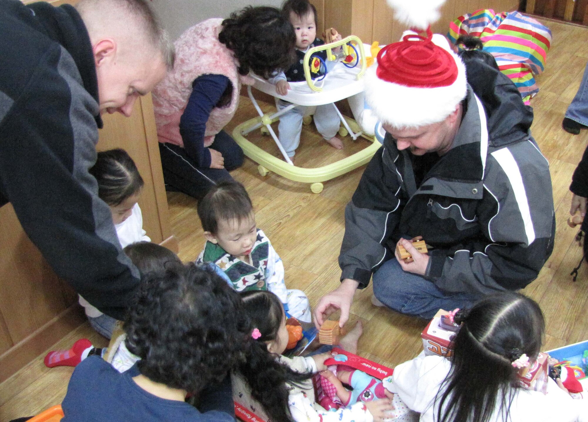 Airmen from the Air Force Technical Applications Center's Detachment 452 present hand-carved wooden cars to boys and girls at the Chechon Children's Home, an orphanage near Wonju, S. Korea.  The cars were a gift from Ed Wares, father of Sabrina Miller, AFTAC's Scientific & Technical Information Program Manager.  Members of the detachment visited the facility Dec. 22. 2012 to distribute gifts to the children. (Courtesy photo)