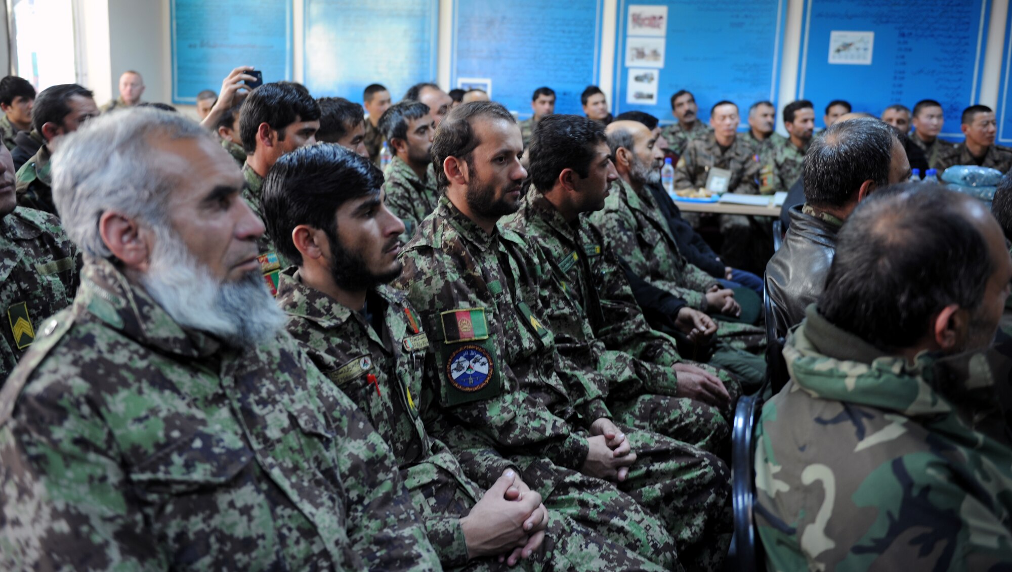 Fellow Afghan Air Force members attend an Mi-17 helicopter ‘Engine & Body’ class graduation Dec. 20, 2012 at Kabul, Afghanistan, International Airport.  Sixteen students graduated after successfully completing 250 hours of training on avionics, engine and aircraft body work. (U.S. Air Force photo/Staff Sgt. Mekpongsatorn)