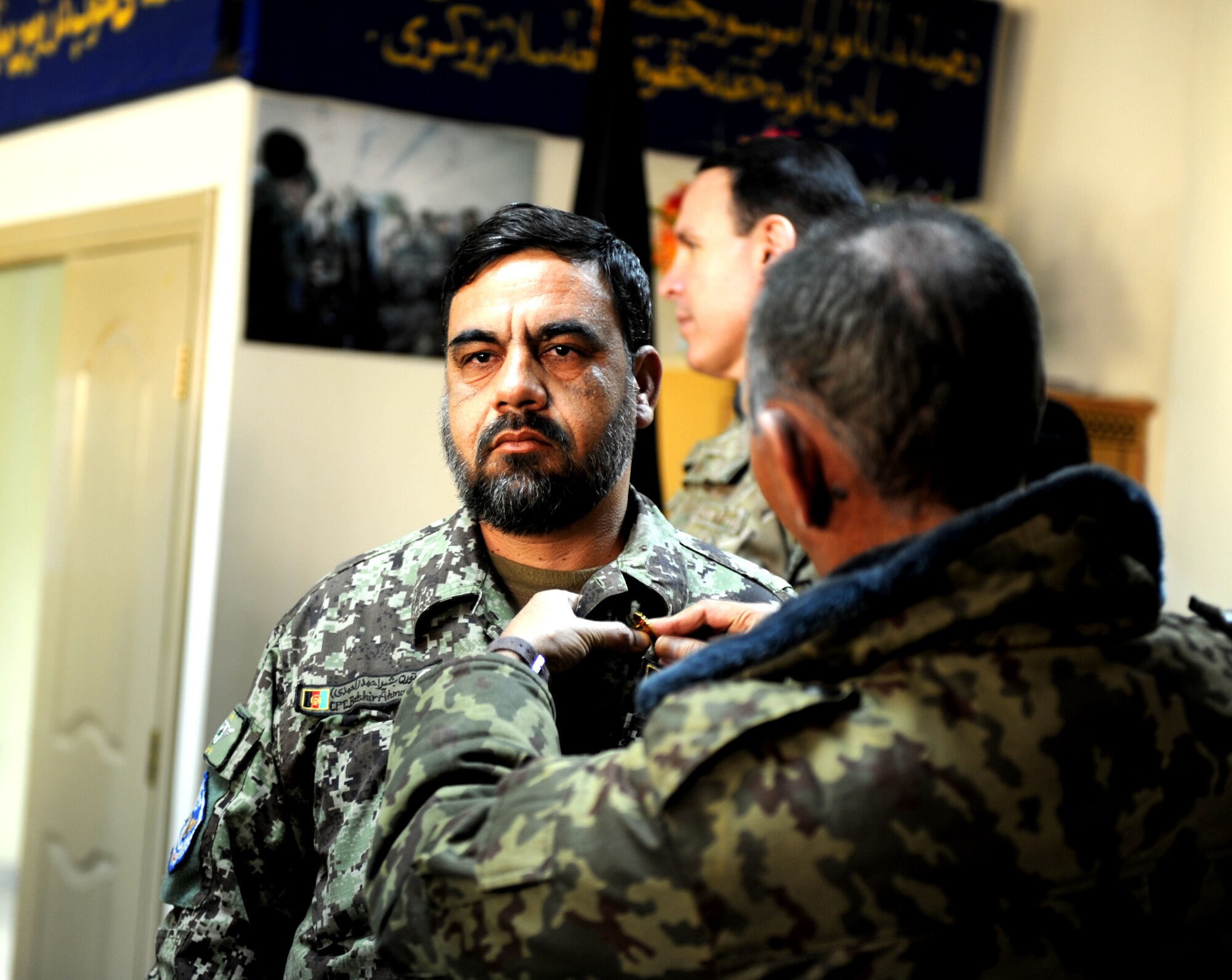 Afghan Air Force Col. Mahmood Rahman (right), commander of Afghanistan’s Air University ‘Pohantoon-e-Hayayee’, places a graduation pin on the uniform of one of the 16 students graduating a nine week Mi-17 helicopter ‘Engine & Body’ class Dec. 20, 2012. Afghan AF instructors partnered with advisors from the Mongolian Air Force to teach students course materials on avionics, engine and aircraft body work. (U.S. Air Force photo/Staff Sgt. Mekpongsatorn)