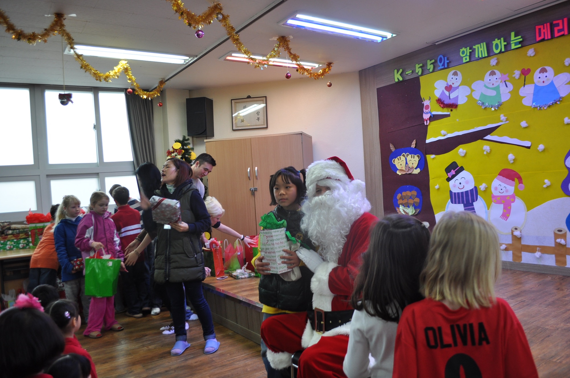 Children from the Ae Hyang Child Welfare Center in Pyeongtaek pose with Santa and receive Christmas presents during the 36th Fighter Squadron’s visit to the orphanage Dec. 15, 2012. The more than 75 service members and families ensured each of the 77 children received a gift. (courtesy photo)