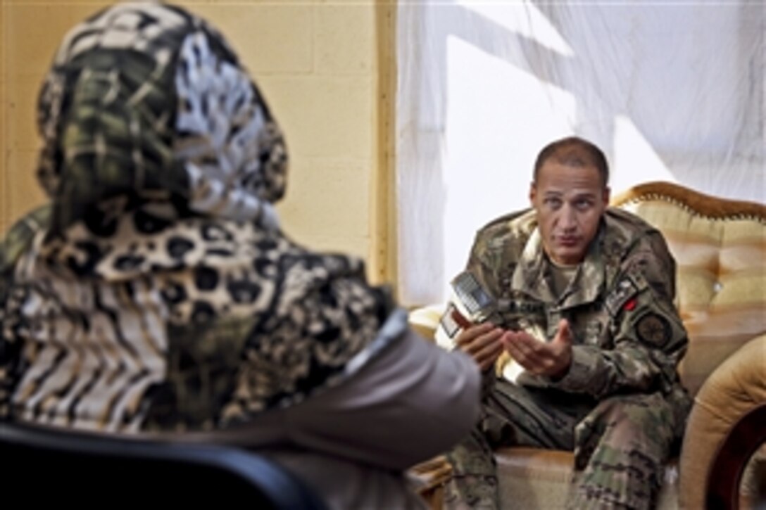 U.S. Navy Cmdr. Louis McCray, right, discusses women's issues and decreasing violence against women in Farah province with a provincial council member during a council meeting at the provincial governor's compound in Farah City, Afghanistan, Jan. 3, 2013. McCray is the commander of Provincial Reconstruction Team Farah.