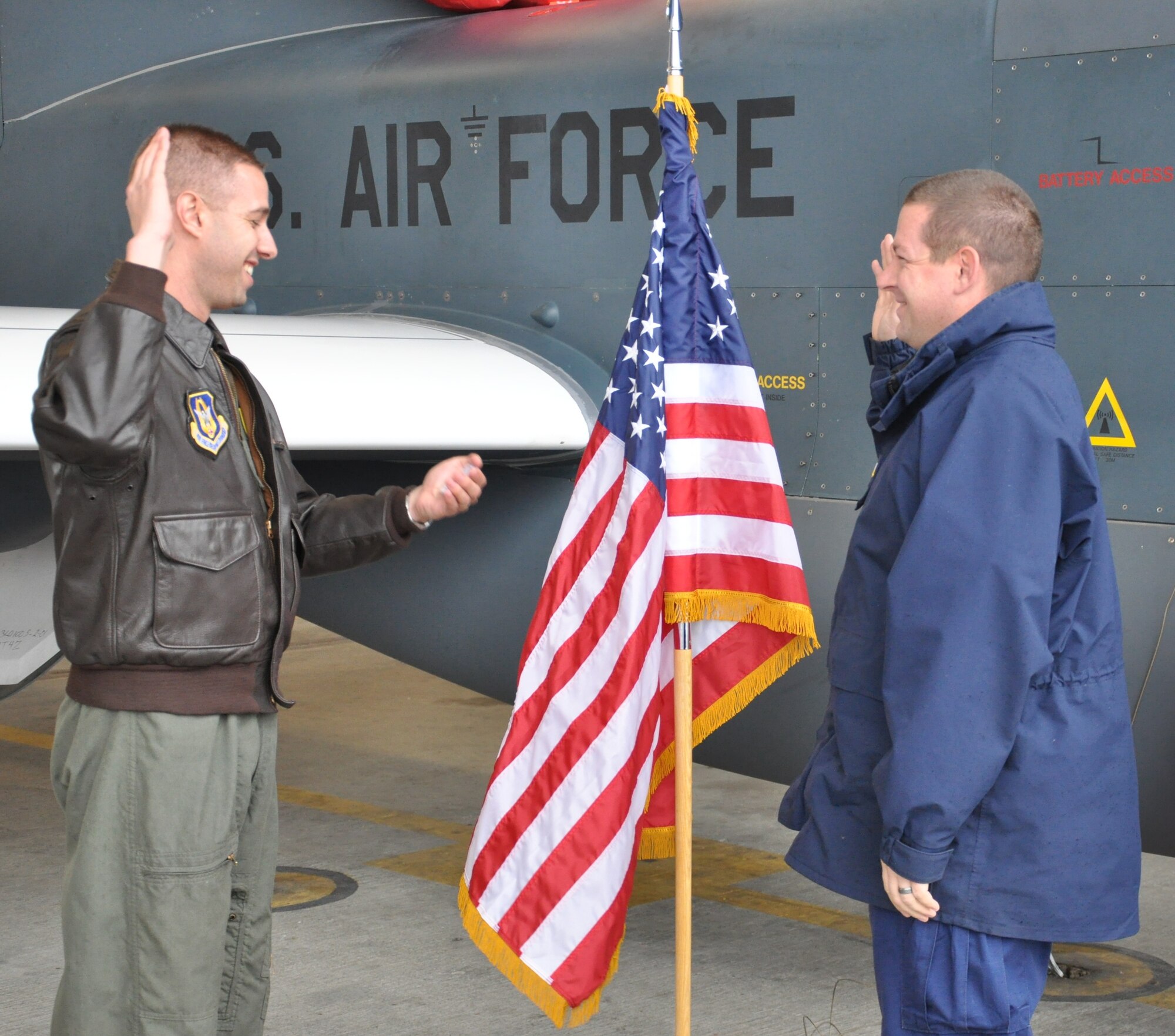 Major Christopher, 940th Wing Executive Officer, administers the oath of enlistment to Coast Guard Petty Officer 1st Class Brian McKenzie, near an RQ-4 Global Hawk at Beale Air Force Base, Calif., on Dec. 21, 2012. The two military members are life-long friends who have managed to stay connected despite taking different career paths in separate branches of service.  (U.S Air Force photo by Senior Airman Adam Hamar)