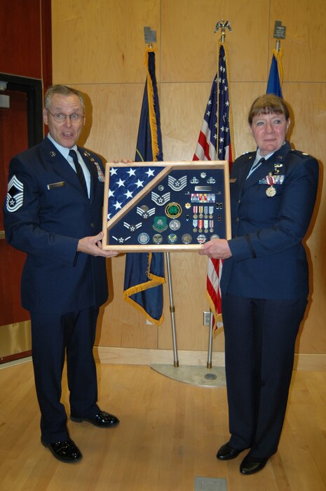 Chief Master Sgt. Steve Schiele presents a shadow box to Lt. Col. Cecilia Nackowski during her retirement ceremony at the Utah Air National Guard Base Dec. 2. Nackowski formally retired after 35 years of military service.(U.S. Air Force photo by Capt. Wayne Lee)(RELEASED)