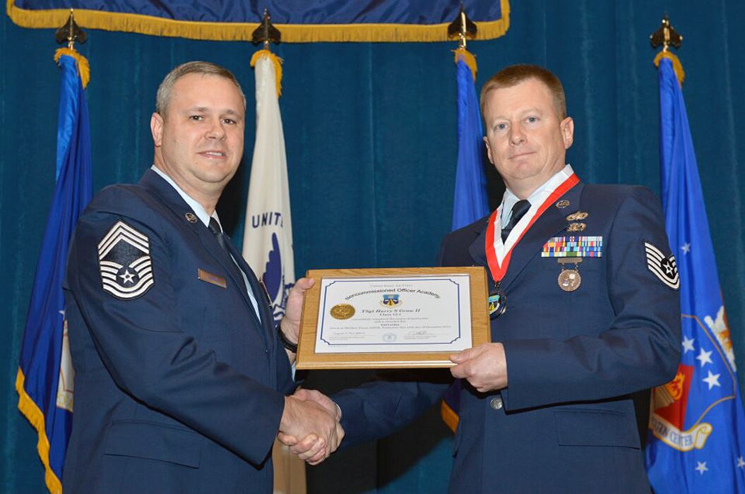 Master Sgt. James E. Pepin awarded the Noncommissioned Officer Academy's distinguished graduate award to Utah Air National Guard member Tech. Sgt. Harry Grow at McGhee Tyson Air National Guard Base, Tenn. on Dec. 12. The distinguished graduate award is presented to students in the top ten percent of the class. It is based on objective and performance evaluations, demonstrated leadership, and performance as a team player. (Air Force photo by Master Sgt. Kurt Skoglund/Released)