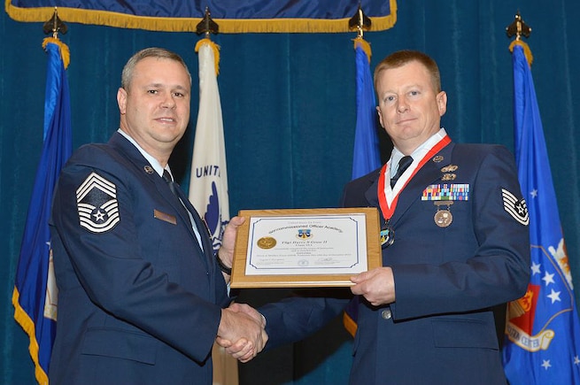 Master Sgt. James E. Pepin awarded the Noncommissioned Officer Academy's distinguished graduate award to Utah Air National Guard member Tech. Sgt. Harry Grow at McGhee Tyson Air National Guard Base, Tenn. on Dec. 12. The distinguished graduate award is presented to students in the top ten percent of the class. It is based on objective and performance evaluations, demonstrated leadership, and performance as a team player. (Air Force photo by Master Sgt. Kurt Skoglund/Released)