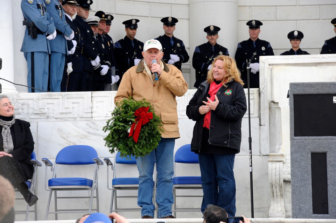 Morrill Worcester and his wife Karen, founder and executive director, Wreaths Across America, addresses thousands of service members and volunteers during the opening ceremony before presenting Mary Byers, president of the Gold Star Mothers, with the "Millionth", wreath at the apatheater at Arlington National Cemetery in Arlington, Va., Dec. 15, 2012.