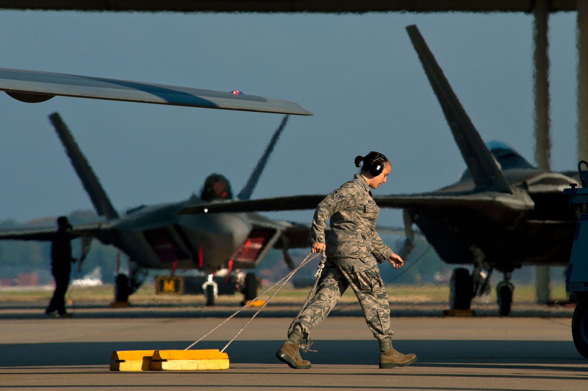 Airman 1st Class Meaghan Mueller, a crew chief, pulls the chocks from beneath an F-22 Raptor on the Joint Base Langley-Eustis flightline before a training mission. (U.S. Air Force photo/Tech. Sgt. Bennie J. Davis III)