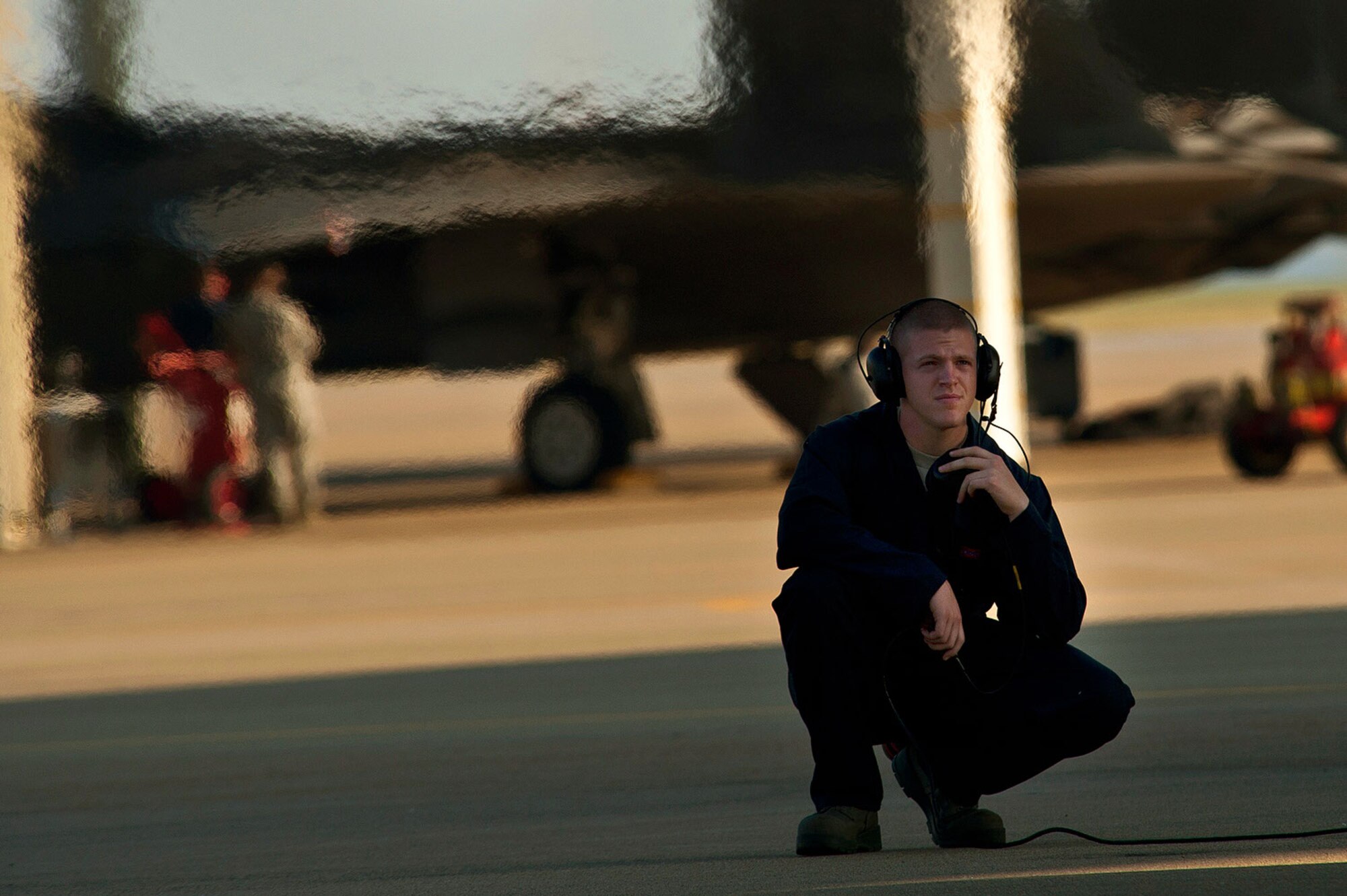 Airman 1st Class Benjamin Speer, an F-22 crew chief, watches over an aircraft and communicates with a pilot during a preflight inspection before a training mission. (U.S. Air Force photo/Tech. Sgt. Bennie J. Davis III)