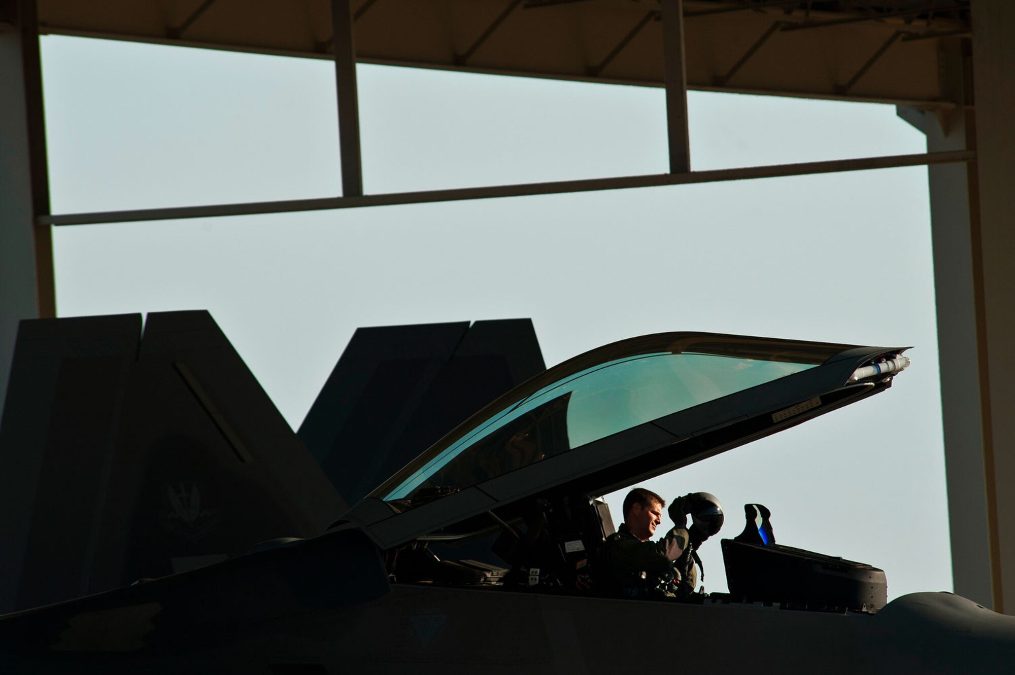 Lt. Col. David Lopez inspects his helmet inside the cockpit of an F-22 Raptor while preparing for takeoff. Lopez is the deputy director of operations for the 1st Operations Support Squadron. (U.S. Air Force photo/Tech. Sgt. Bennie J. Davis III)