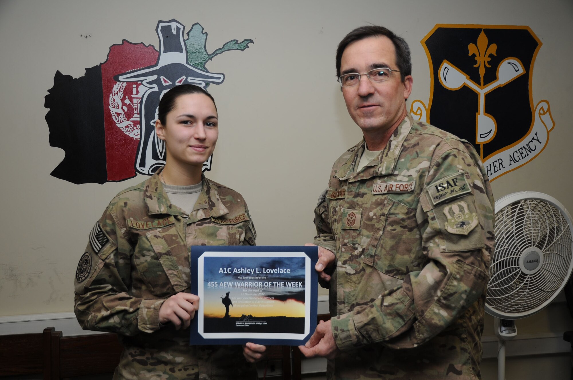 BAGRAM AIRFIELD, Afghanistan - Chief Master Sgt. Steve Bohannon, Command Chief Master Sergeant of the 455th Air Expeditionary Wing, presents the "Warrior of the Week" award to Airman 1st Class Ashley Lovelace, 455th Expeditionary Operations Support Squadron intelligence specialist, Jan. 5, 2013. Lovelace helped to keep the Mission Planning Cell where she works running smoothly after her NCOIC had to go on emergency leave. (U.S. Air Force photo/Staff Sgt. David Dobrydney)