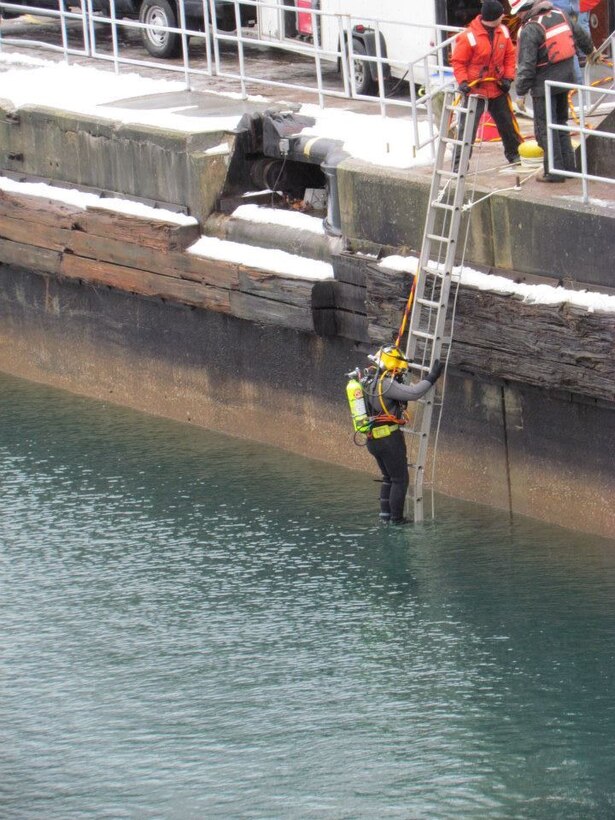 A diver uses a ladder to climb into the 37-degree water to reach the MacArthur Lock floor where he will inspect the areas around the gates and valves and assist with debris removal. This is done annually as a part of the Soo Locks winter maintenance.
