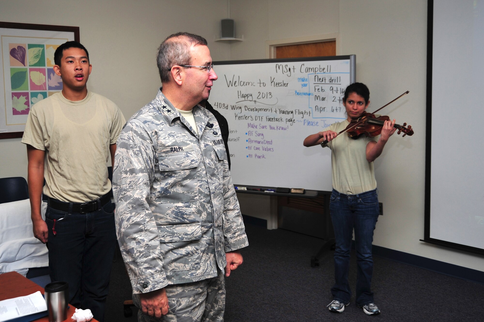 Maj. Gen. Donald C. Ralph, Mobilization Assistant to the Commander, U.S. Air Forces Europe, sings the Air Force Song with members of the 403rd Wing Development and Training Flight while Airman 1st Class Kelly Andino, 403rd Operations Group all source intelligence specialist, accompanies on the violin. Ralph visited with wing members during the Jan. 5-6, 2013, to stress the importance of education, mentorship, and job success.  (U.S. Air Force photo/Tech. Sgt. Ryan Labadens)