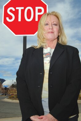 Teresa Beasley poses in front of a sign to reinforce the goal to stop sexual assaults. Beasley is the Air Force Academy's sexual assault response coordinator. (U.S. Air Force photo/Don Branum)