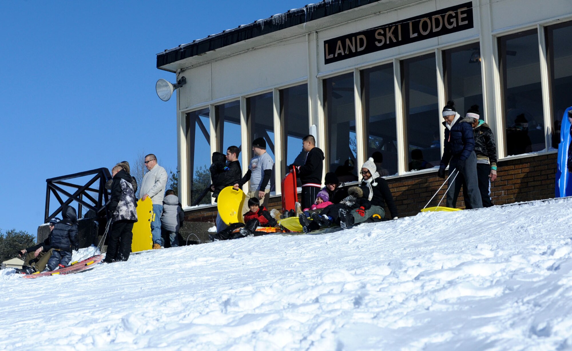 Military members and their families enjoy an afternoon of sledding outside the Land Memorial Ski Lodge at Misawa Air Base, Japan, Jan. 5, 2013. The ski lodge opened to snow enthusiasts on Friday, Jan. 5, 2013 for the winter season. Along with a free place to sled, ski and snowboard, private reservations can be made on the weekends for small group gatherings. (U.S. Air Force photo by Airman 1st Class Kenna Jackson)