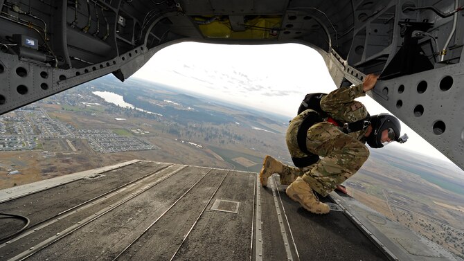 Tech. Sgt. Jason Martinez leans out the back of a CH-47 Chinook helicopter above Fairchild Air Force Base, Wash., Nov. 6, 2012. Martinez looks for a target on the ground, which indicates where the jumpers will exit the aircraft. Martinez is a survival, evasion, resistance and escape specialist with the 336th Training Group. (U.S. Air Force photo/Airman 1st Class Ryan Zeski)