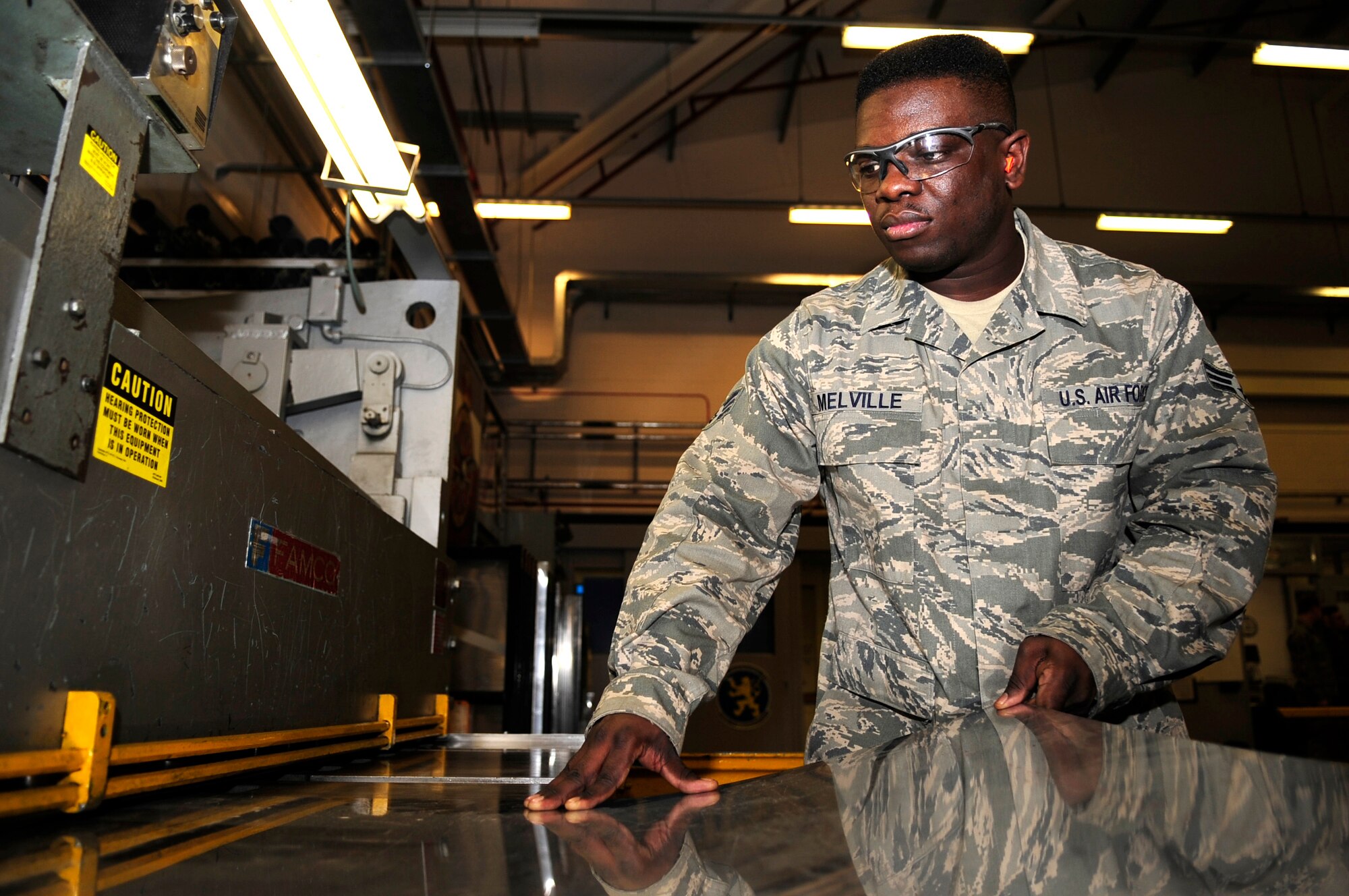 Senior Airman Theo Melville, 100th Maintenance Squadron aircraft structural maintainer from Princeton, N.J., prepares to slide a piece of sheet metal through a power shear to cut it down to a useable size, Jan. 8, 2013, in the sheet metal shop on RAF Mildenhall, England. The cut metal will be used as a patch on an aircraft. (U.S. Air Force photo by Airman 1st Class Dillon Johnston/Released)