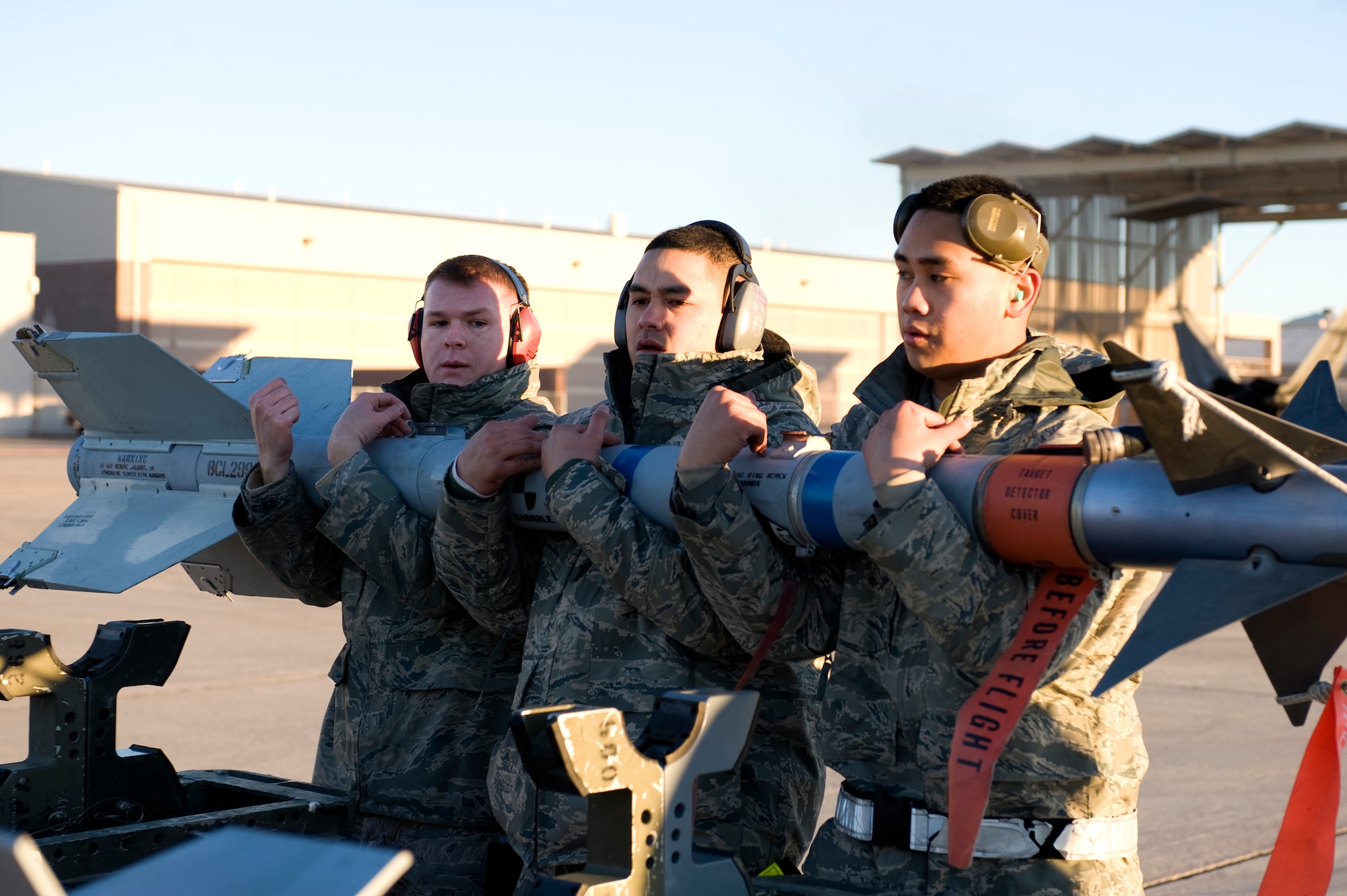 Airman 1st Class Ben Wilsey, Staff Sgt. Treston Kaneao, and Airman 1st Class Ryan Duarte, 57th Aircraft Maintenance load crew members, prepare to load an AIM-9 Sidewinder to an F-16 Fighting Falcon, during a quarterly load crew competition, Jan. 4, 2013, at Nellis Air Force Base, Nev. The members of the winning unit receive three days off designated by the 57th Wing Commander, a traveling trophy, and bragging rights until the next competition.  (U.S. Air Force photo by Senior Airman Matthew Lancaster)
