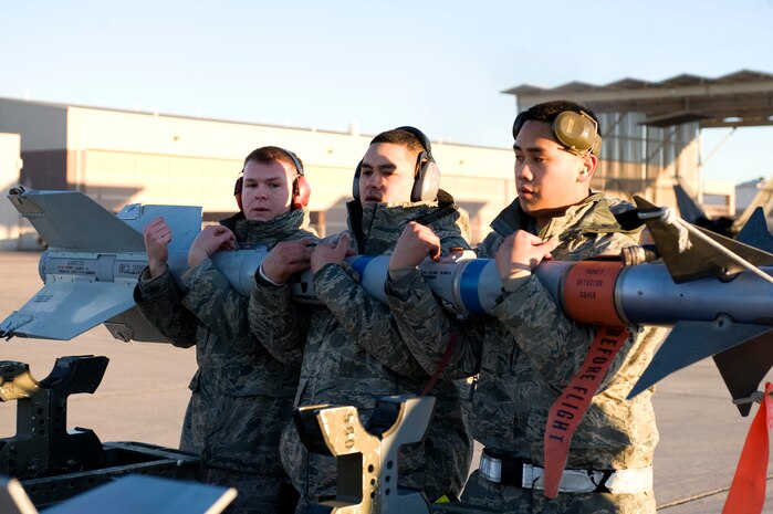 Airman 1st Class Ben Wilsey, Staff Sgt. Treston Kaneao, and Airman 1st Class Ryan Duarte, 57th Aircraft Maintenance load crew members, prepare to load an AIM-9 Sidewinder to an F-16 Fighting Falcon, during a quarterly load crew competition, Jan. 4, 2013, at Nellis Air Force Base, Nev. The members of the winning unit receive three days off designated by the 57th Wing Commander, a traveling trophy, and bragging rights until the next competition.  (U.S. Air Force photo by Senior Airman Matthew Lancaster)
