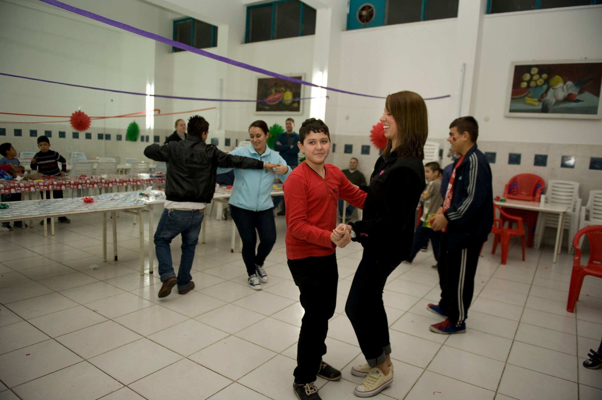 Airmen from the 90th Expeditionary Air Refueling Squadron dance with children at the Seyhan Isitme Engelliler Ilkogretim Okulu (Seyhan Hearing Impaired Primary School) Dec. 27, 2012, in Adana, Turkey. Members of the 90th EARS annually organize a party for children who attend the Seyhan School and also volunteer weekly at facilities in Adana to contribute to the community. (U.S. Air Force photo by Staff Sgt. Marissa Tucker/Released)