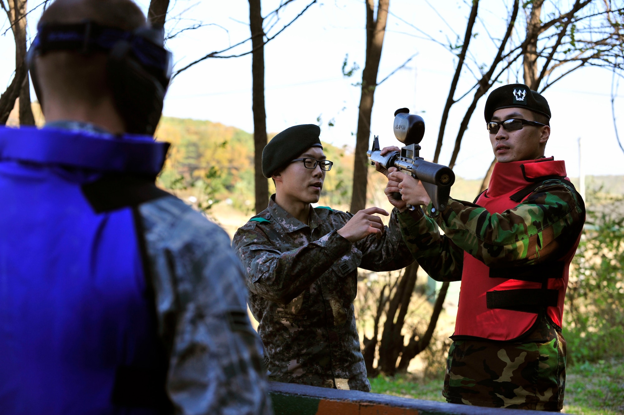Cpl. Choi, Hyukjun (left), and Capt. Kim, Jongwook, Republic of Korean Army 4th Battalion 169th Regiment soldiers, instruct 51st Security Forces Squadron defenders on equipment before participating in a joint training paintball exercise Nov. 1, 2012. The training helped familiarize tactics from both units by integrating teams for a friendly, competitive game of capture the flag. (U.S. Air Force photo/Airman 1st Class Alexis Siekert)