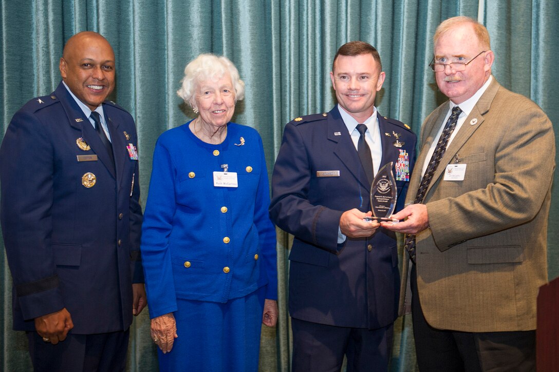 Maj. Kenneth Holmes, Air Force Special Operations Command chief of space training, second from right, receives the first annual Forrest S. McCartney National Defense Award from Jim McCarthy, far right, the NSC Chairman, at a luncheon held Tuesday. Also pictured are Brig. Gen. Anthony Cotton, 45th Space Wing commander, and Mrs. Ruth McCartney, the widow of Air Force Lt. Gen. Forrest S. McCartney. The three-star was the former director of Kenney Space Center. (U.S. Air Force photo/ Cory Long)