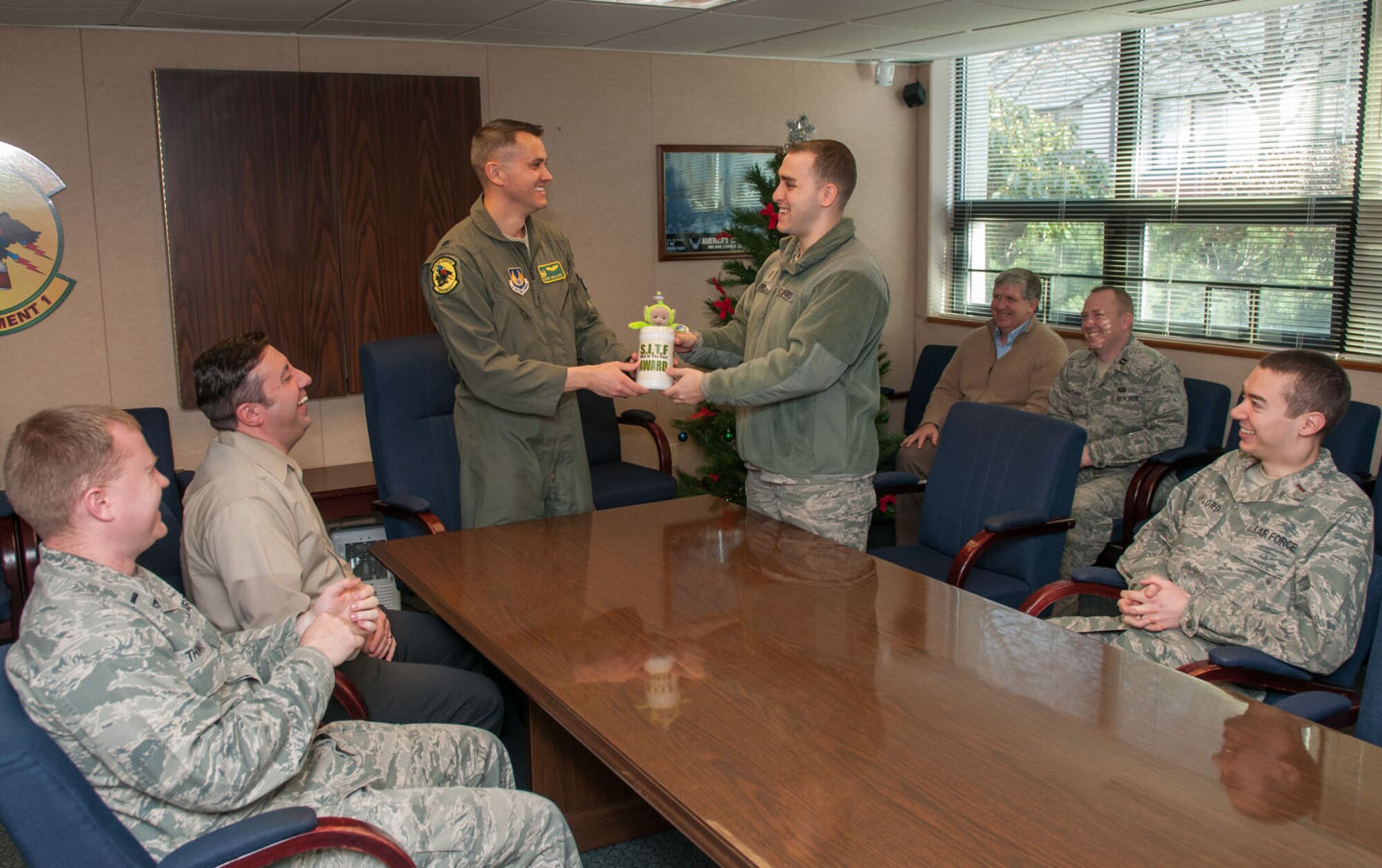 HANSCOM AIR FORCE BASE, Mass. – Lt. Col. David McIllece hands the 46th Test Squadron, Detachment 1, “Shot in the Foot” award to 2nd Lt. Ben Libner Jan. 8. The SITF award is one example of how heritage and tradition is recognized in the Air Force. (U.S. Air Force photo by Rick Berry) 