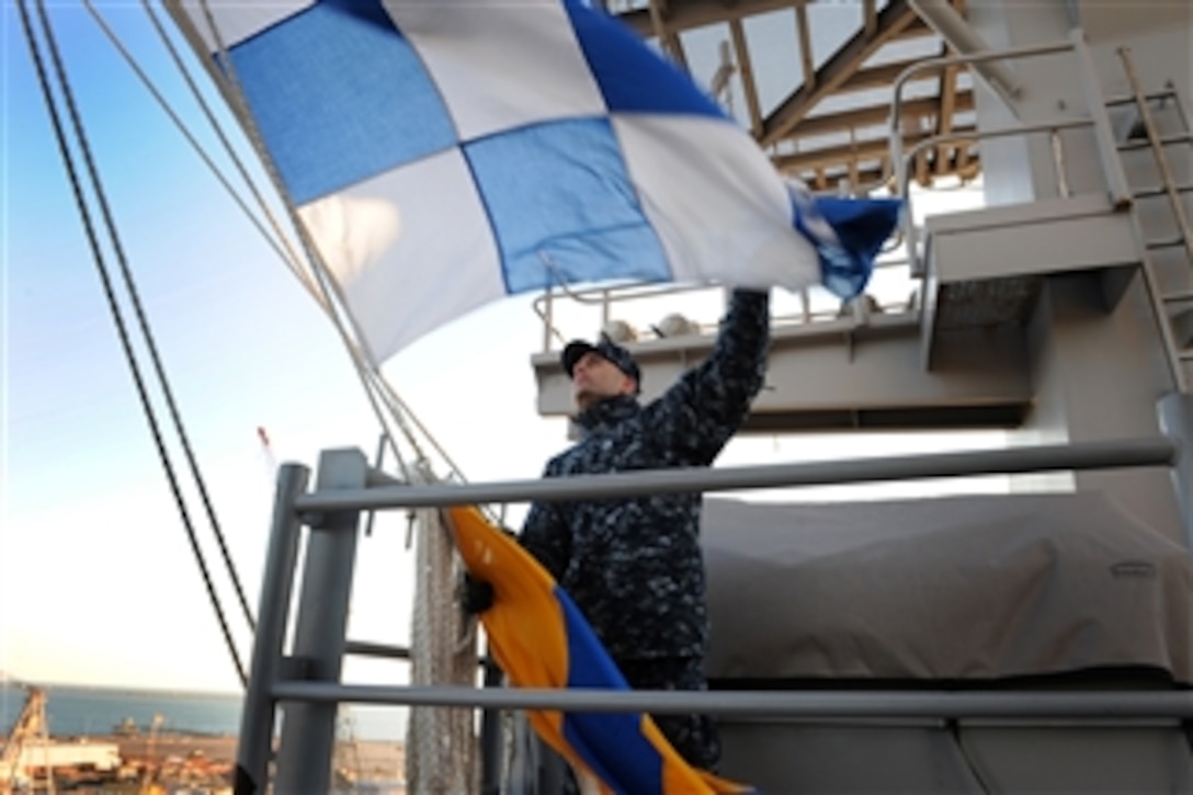 U.S. Navy Petty Officer 2nd Class Juan M. Cardova hoists the ship's call sign in signal flags from the signal bridge of the aircraft carrier USS George H.W. Bush (CVN 77) at Naval Station Norfolk, Va., on Jan. 7, 2013.  The carrier is getting underway to conduct training and carrier qualifications in the Atlantic Ocean.  
