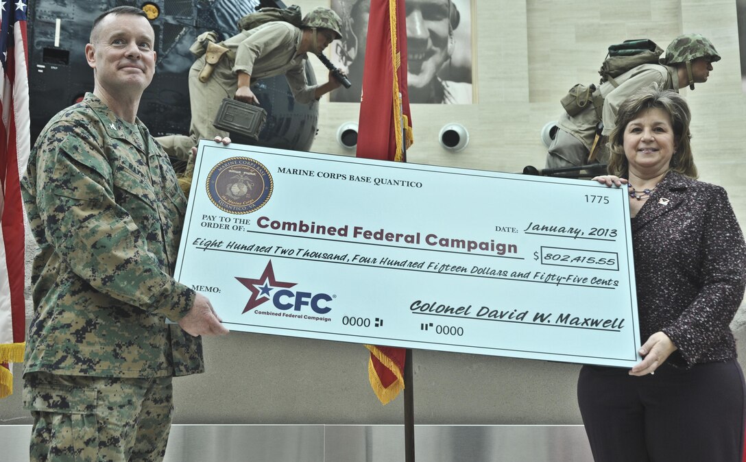 TRIANGLE, Va. (Jan. 9.) - Col. David W. Maxwell, base commander, Marine Corps Base Quantico, presents Tammi Ellis, Potomac Region Combined Federal Campaign representative, with a check during the CFC Close Out Celebration and Award Ceremony at the National Museum of the Marine Corps on Jan. 9. The units on base raised a total of $802,415.55 and exceeded their goal by 23 percent. (U.S. Marine Corps photo by Lance Cpl. Antwaun L. Jefferson/Released)