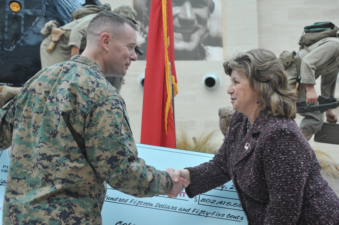 Tammi Ellis, Potomac Region Combined Federal Campaign representative, congratulates Col. David W. Maxwell, base commander, Marine Corps Base Quantico, on a job well done as he presents her with a check during the CFC Close Out Celebration and Award Ceremony at the National Museum of the Marine Corps on Jan. 9. The check totaled $802,415.55. 
