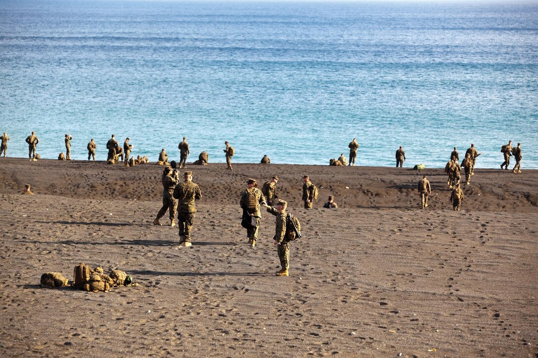 Marines and sailors gather on the beaches of Iwo To Dec. 19 during a professional military education tour. While on the beach, Marines were reminded of the initial assault that took place and reflected on those who fought gallantly.