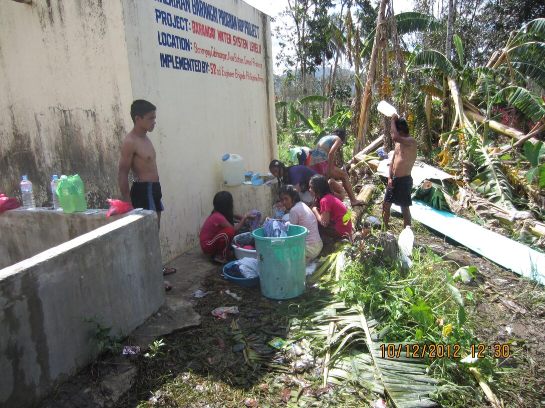 A community devastated by Typhoon Bopha uses water funneled from a mountain for bathing and washing laundry here Dec. 10. The Armed Forces of the Philippines and the U.S. Marine Corps Forces, Pacific Experimentation Center joined to gather operational feedback on water purification systems and while providing relief efforts to typhoon victims.