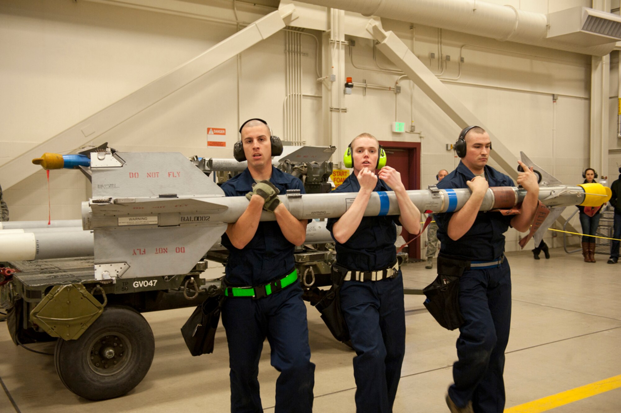 Senior Airman 1st Class Swartzwelder, Senior Airman Philip Bennett and Senior Airman John Grimes, 525th Aircraft Maintenance Unit, load an AIM-9 Sidewinder missile during a 3rd Wing weapons load competition. (U.S. Air Force photo/Staff Sgt. Robert Barnett)