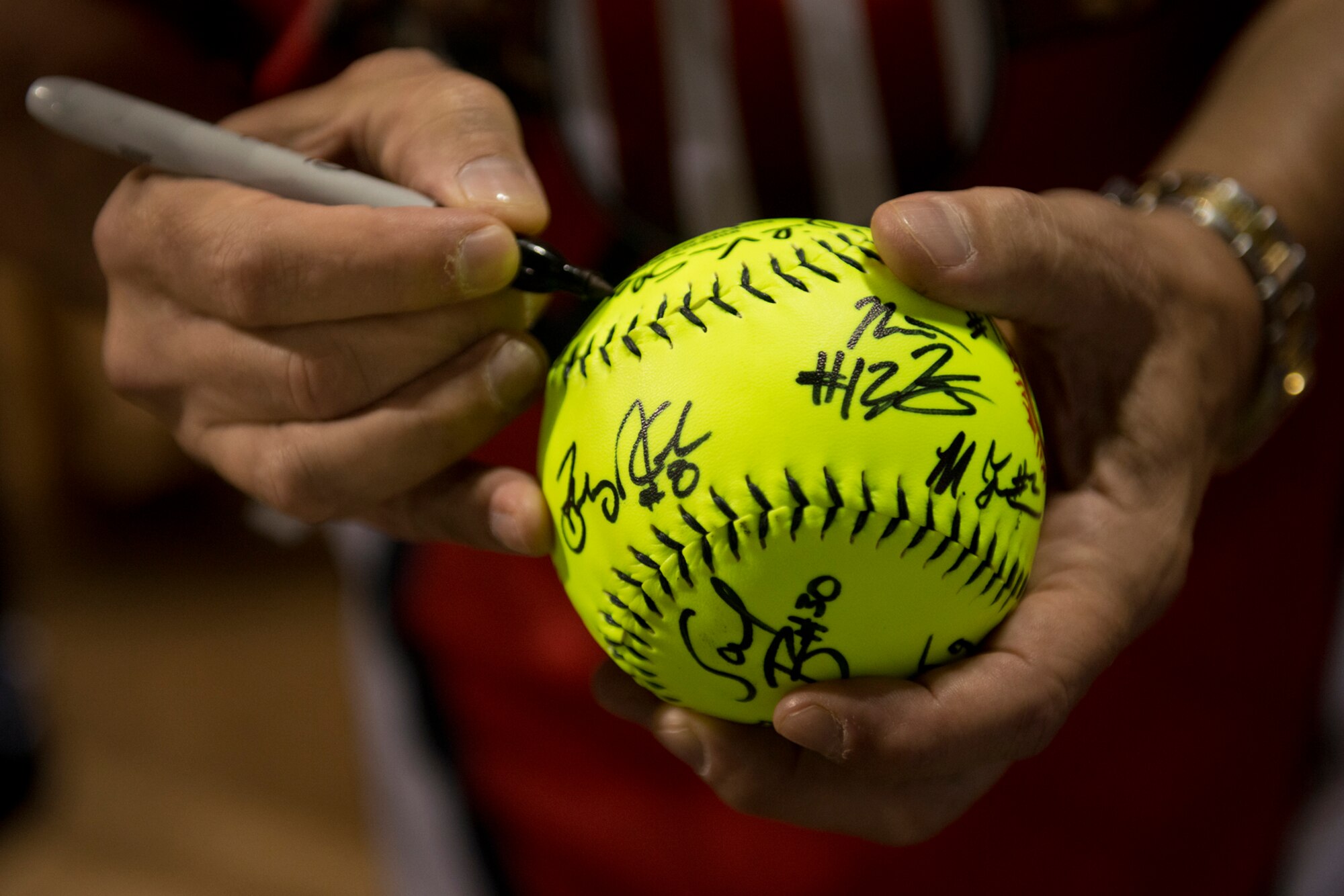 A member of the Wounded Warrior Amputee Softball Team signs an autograph for Airman Basic Ken Oliver, 15th Maintenance Squadron, Jan. 8, 2013, at Milican Field, Joint Base Pearl Harbor-Hickam, Hawaii. Oliver was one of two Airmen selected to throw out the ceremonial first pitch. The WWAST is comprised of competitive, athletic veterans and active duty servicemembers who have lost limbs during post-9/11 combat operations. The team includes individuals with a variety of amputations of the arm, above knee, below knee, bilateral below knee, and foot. Some are still in the service, while others are attending college thanks to the Post-9/11 GI Bill while others have moved on to new careers. (U.S. Air Force photo/Staff Sgt. Mike Meares)