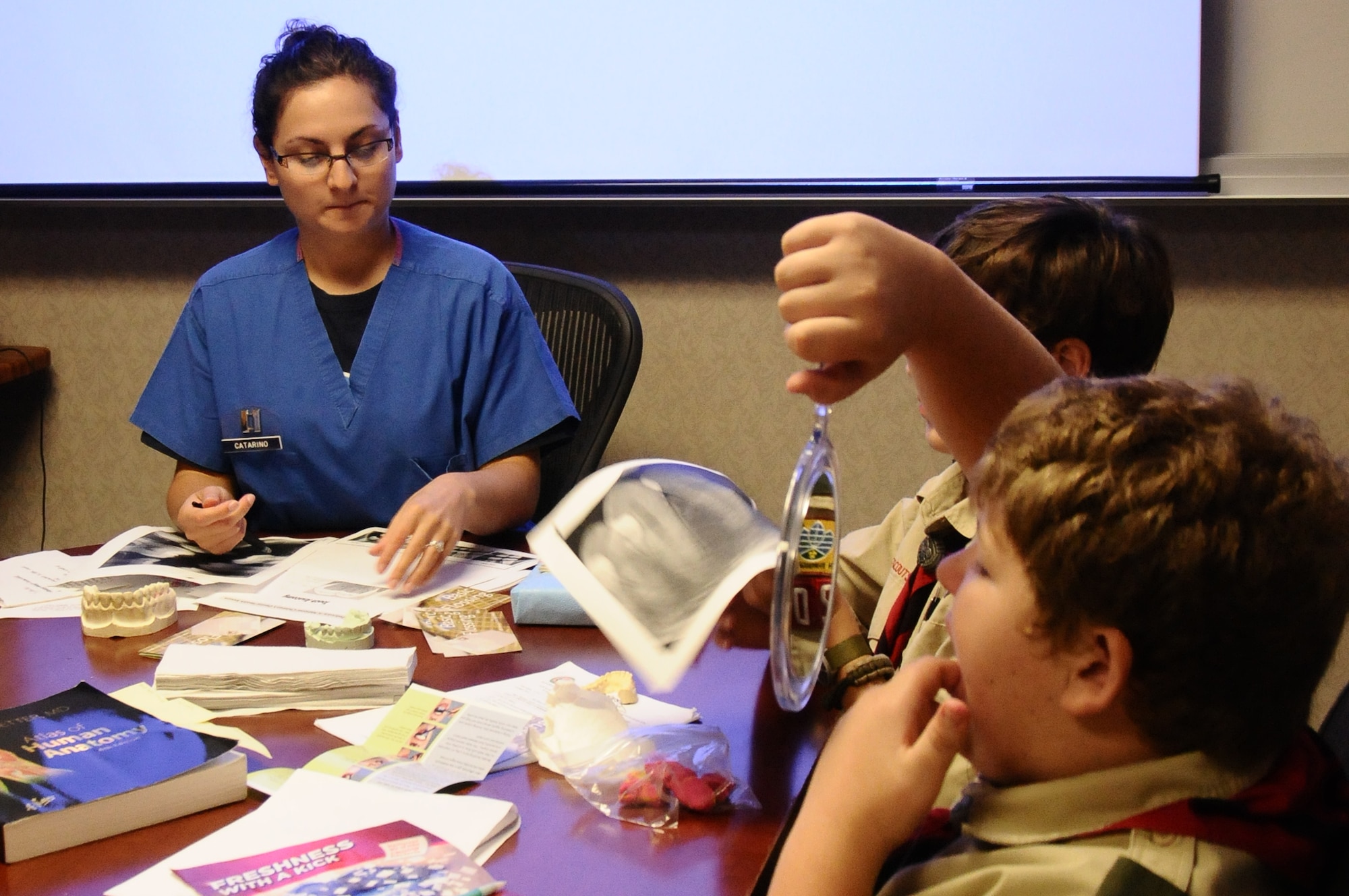 A member of Boy Scouts Troop 20 inspects his teeth, while Capt. Nicole Catarino, 36th Medical Group dental officer, explains the importance of oral health and goes over X-rays at Andersen Air Force Base, Guam, Jan. 4. The Boy Scouts attended the presentation to gain awareness and recognize the importance of good dental habits at an early age. February is National Children’s Dental Health Month. (U.S. Air Force photo by Airman 1st Class Mariah Haddenham/Released)