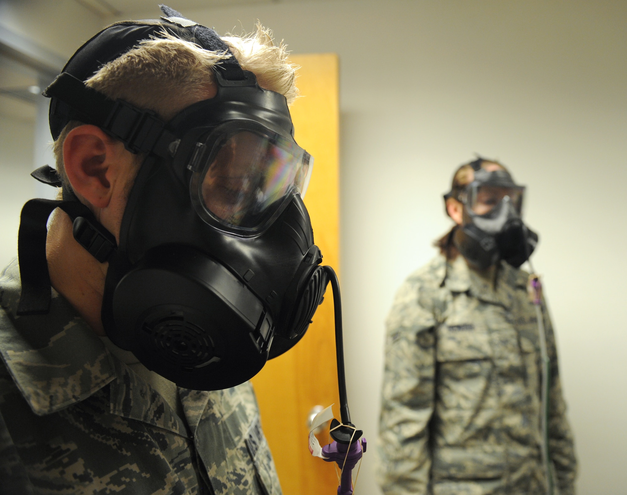 Senior Airman Nicholas McRae, 2nd Aircraft Maintenance Squadron crew chief, and Airman 1st Class Nichole DeMoss, 2nd Operations Support Squadron airfield management, conduct a breathing exercise during a gas mask fit test on Barksdale Air Force Base, La., Jan. 10. During the test, a Photocount Plus machine measures the particle readings from the air in the room and compares it to the air found in the gas masks to ensure the masks are sealed properly. (U.S. Air Force photo/Airman 1st Class Benjamin Gonsier)
